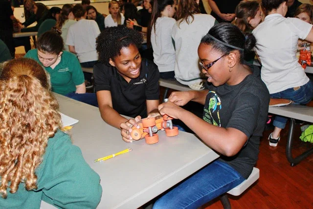 Two school aged girls putting together a roller skate during their STEM field trip