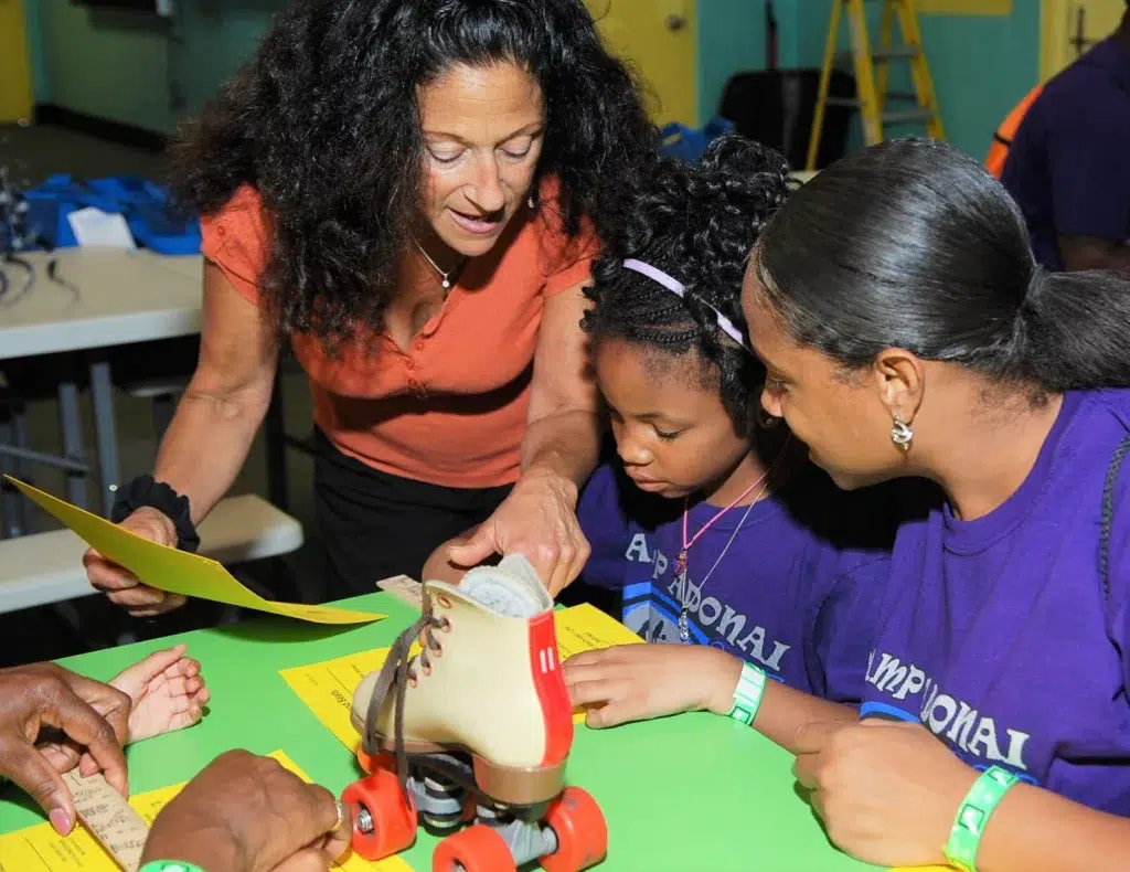 Teacher going over a STEM lesson with a mother and daughter on roller skates