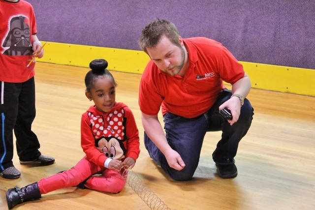 STEM teacher showing a grade schooler an experiment at a roller rink